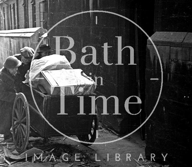 An elderly couple are helped moving their possessions along Bridewell Lane, Bath 1942