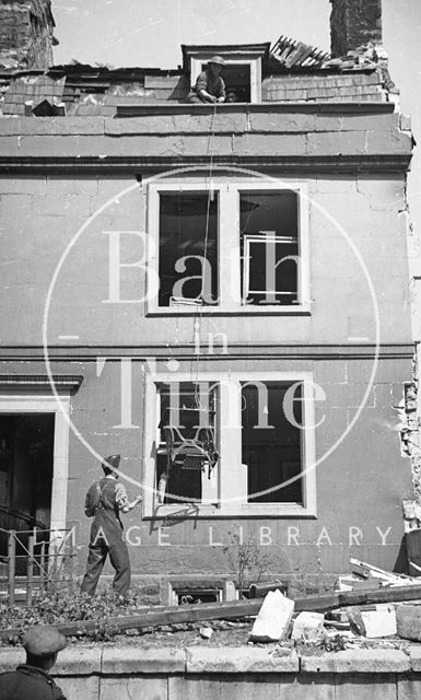 A sewing machine being lowered down from a bombed building, Bath 1942