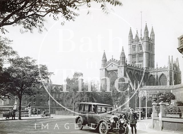 A chauffeur waits beside his car outside the Empire Hotel, Orange Grove, Bath c.1932