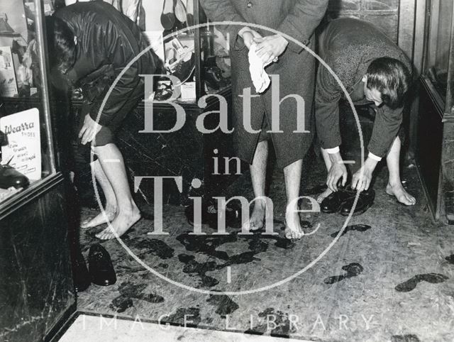 Taking off their shoes in a Bath shop doorway in the flood of 1960