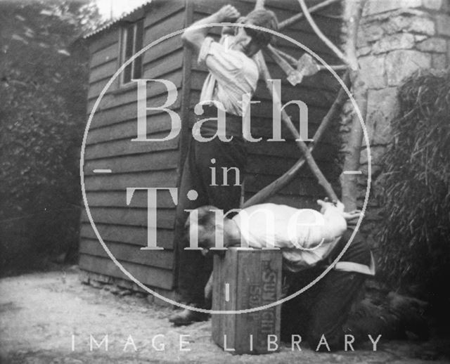 Herbert Noad pretends to behead Walter Noad in the garden behind Noad's Bakery, Bloomfield Road, Odd Down, Bath c.1950