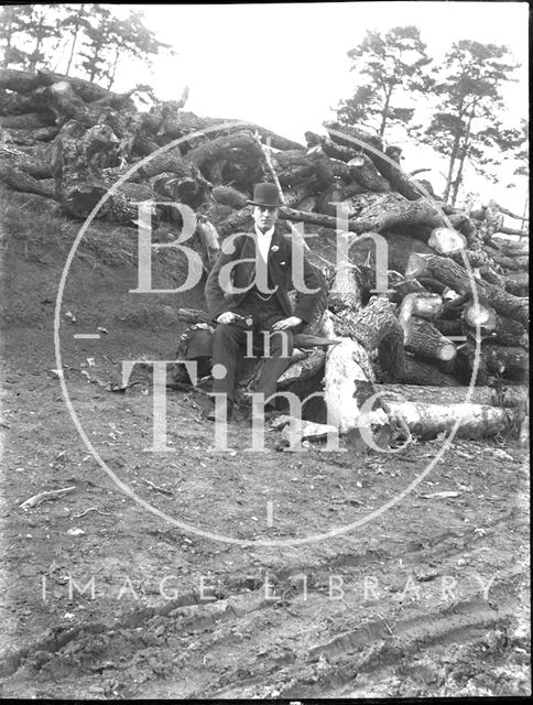 An unidentified gentleman posing in front of a pile of logs c.1900