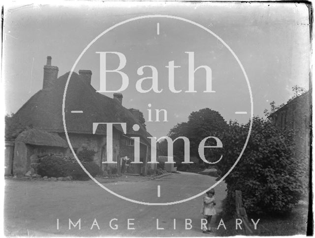 An unidentified village street with child and thatched cottage c.1920