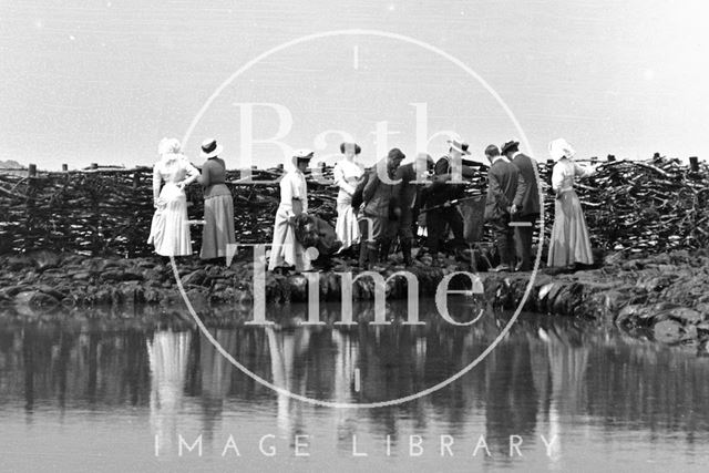 A fine group of people watching a man with a fishing net at Lynmouth, Exmoor, Devon c.1910