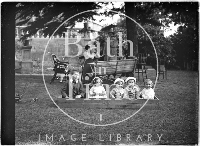 Children and their nanny in a garden paying c.1910