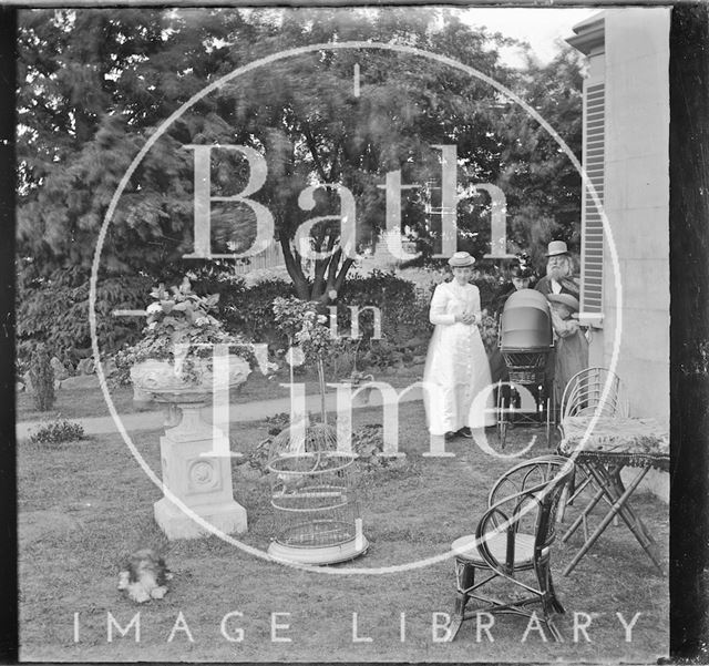 Two people and a pram in the garden of an unidentified house c.1900