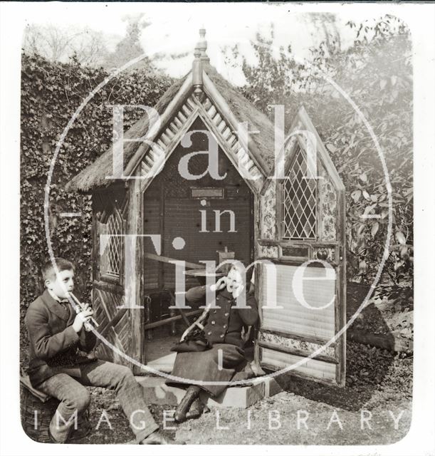 A boy and a girl outside a rustic garden hut c.1890