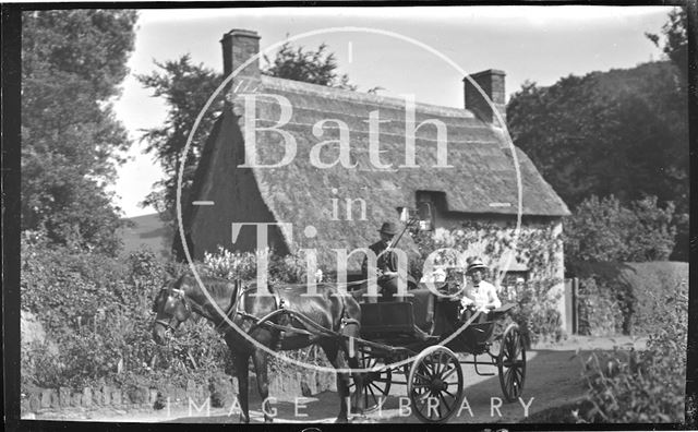 A lady in a horse-drawn carriage outside a thatched cottage near Minehead, Somerset 1914