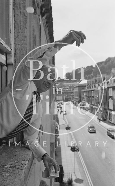 Toy master Eric Snook sprinkling rose petals out of the window, James Street West, Bath 1977