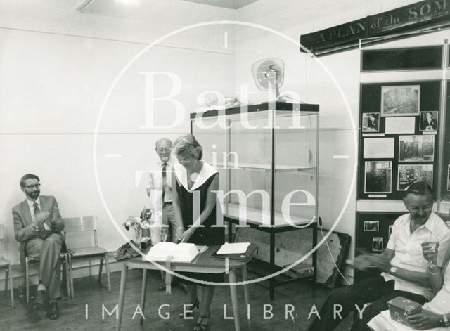 Jane Carey (Lending Library Senior Assistant) cuts cake celebrating 60th birthday, in Moore Room of Bath Reference Library 1984