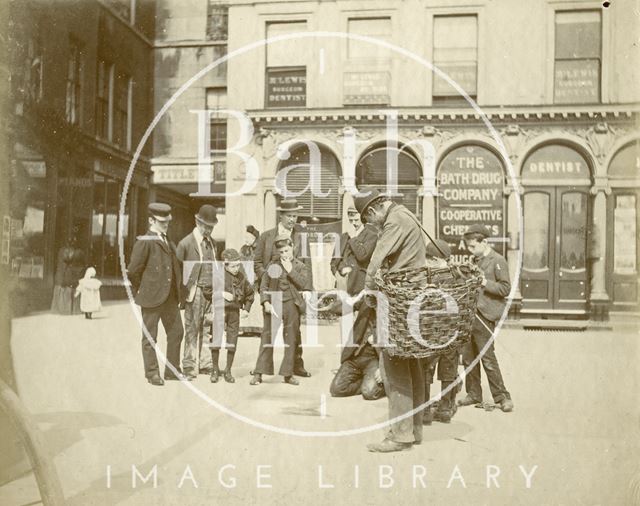 A gathering in Abbey Church Yard outside the Bath Drug Company chemist shop, Bath c.1895