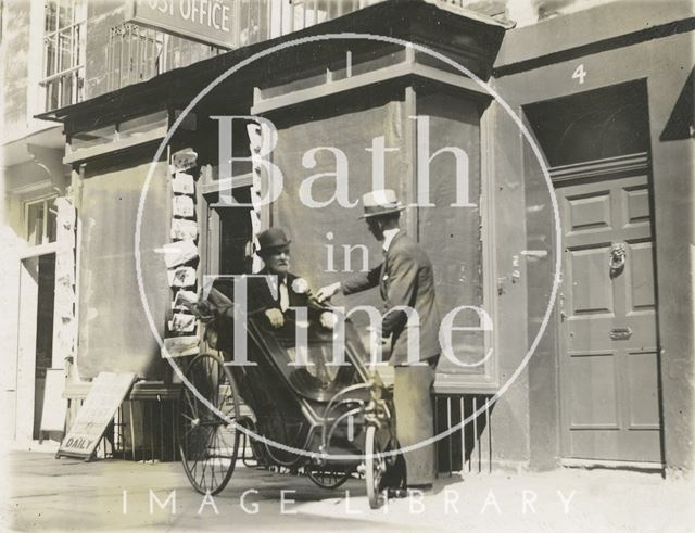 A man in a Bath chair outside the Post Office in Margaret's Buildings, Bath c.1930