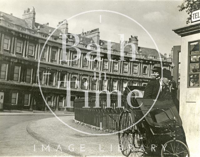 A man in a Bath chair uses the public telephone that used to be at the end of Brock Street on the Circus, Bath c.1930