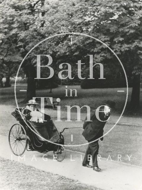 A gentleman pulls a lady in a Bath chair in Royal Victoria Park, Bath c.1910