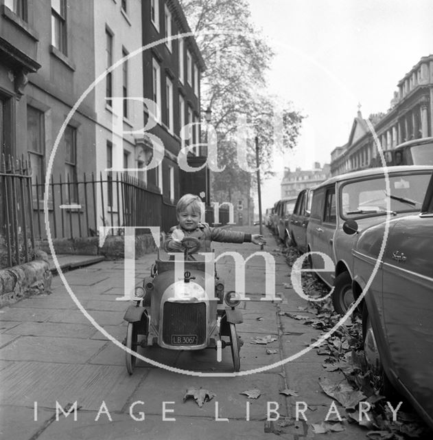 A child in a bull nose Morris pedal car, Old King Street, Bath 1970