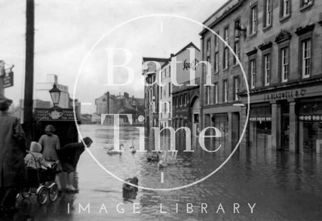 Swans swimming at a flooded Broad Quay, Bath 1960